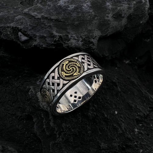 La bague « Rétro – Bijou Original » est une bague en argent qui ne passe pas inaperçue, ornée de motifs complexes de nœuds celtiques et de touches spiralées dorées, le tout mis en valeur avec élégance sur une surface en pierre sombre et texturée.